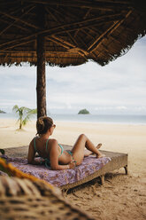 Frau im Bikini entspannt auf dem Bett am Strand - CAVF55768