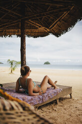 Woman in bikini relaxing on bed at beach - CAVF55768