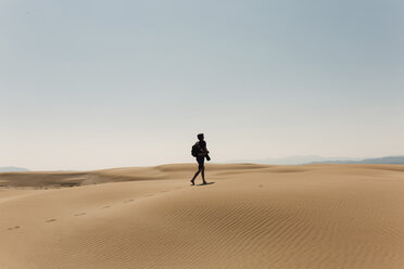 Full length of hiker with backpack exploring desert against sky - CAVF55799