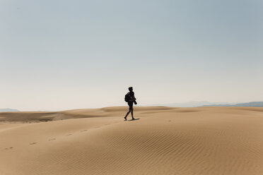 Wanderer mit Rucksack, der die Wüste erkundet, in voller Länge gegen den Himmel - CAVF55799