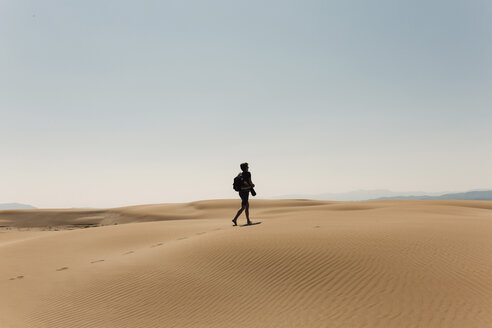 Wanderer mit Rucksack, der die Wüste erkundet, in voller Länge gegen den Himmel - CAVF55799