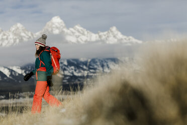 Seitenansicht einer Wanderin mit Rucksack vor schneebedeckten Bergen - CAVF55829