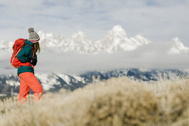 Wanderin mit Rucksack und Blick auf schneebedeckte Berge - CAVF55830