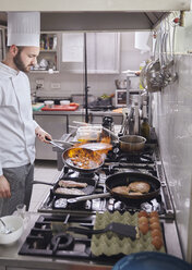 Koch hält brennende Pfanne bei der Zubereitung von Speisen in einer Großküche - CAVF55856