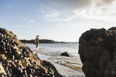 Frankreich, Bretagne, junge Frau mit Surfbrett läuft im Meer - UUF15892