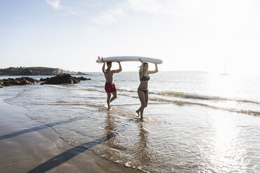 Frankreich, Bretagne, junges Paar mit einem SUP-Board am Meer - UUF15919
