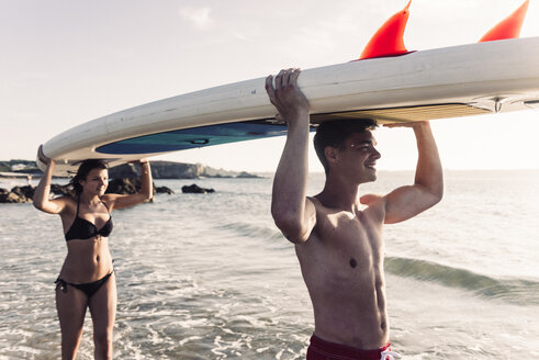 Frankreich, Bretagne, glückliches junges Paar mit einem SUP-Board am Meer - UUF15922