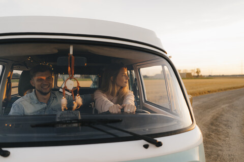 Ehepaar fährt Wohnmobil auf unbefestigtem Weg in ländlicher Landschaft, lizenzfreies Stockfoto