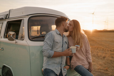Young couple kissing at camper van in rural landscape - GUSF01413
