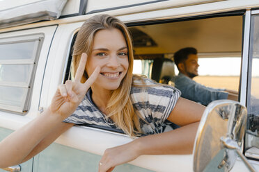 Porträt einer glücklichen Frau, die sich aus dem Fenster eines Wohnmobils lehnt, in dem ein Mann fährt - GUSF01415