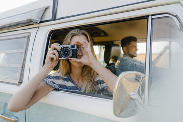 Woman taking picture out of window of a camper van with man driving - GUSF01422