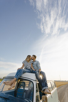 Paar küsst sich auf dem Dach eines Wohnmobils in ländlicher Umgebung - GUSF01443