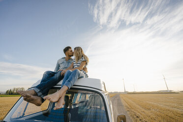 Paar küsst sich auf dem Dach eines Wohnmobils in ländlicher Umgebung - GUSF01445