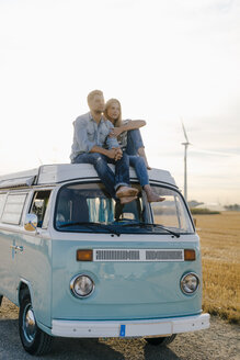 Verliebtes junges Paar auf dem Dach eines Wohnmobils in ländlicher Landschaft - GUSF01448