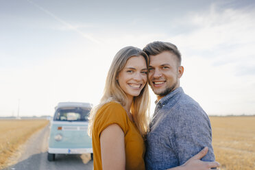 Portrait of smiling young couple at camper van in rural landscape - GUSF01464