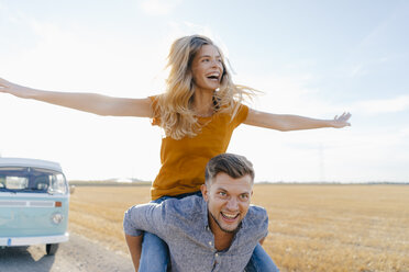 Playful young couple at camper van in rural landscape - GUSF01468