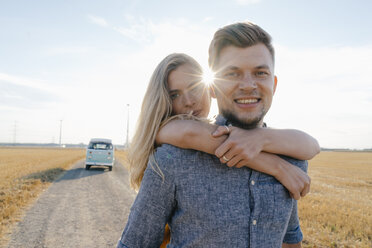 Portrait of happy young couple at camper van in rural landscape - GUSF01470