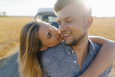 Affectionate young couple at camper van in rural landscape - GUSF01473