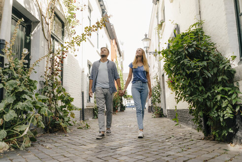 Niederlande, Maastricht, junges Paar geht Hand in Hand in einer Gasse - GUSF01495