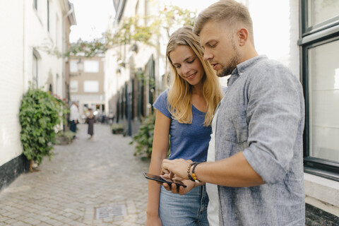 Netherlands, Maastricht, young couple looking at cell phone the city stock photo