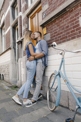 Zärtliches junges Paar küsst sich auf dem Bürgersteig in der Stadt - GUSF01499