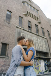 Zärtliches junges Paar, das sich in der Stadt vor einem Kino küsst - GUSF01501