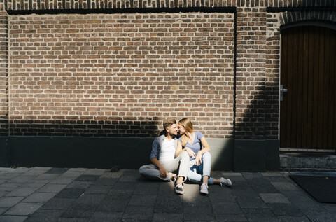 Niederlande, Maastricht, junges Paar, das eine Pause in der Stadt macht und auf dem Bürgersteig sitzt, lizenzfreies Stockfoto