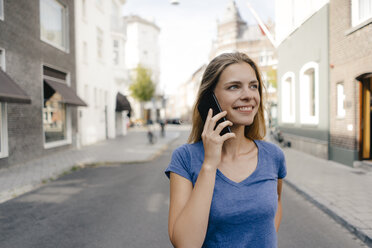 Netherlands, Maastricht, smiling young woman on cell phone in the city - GUSF01503
