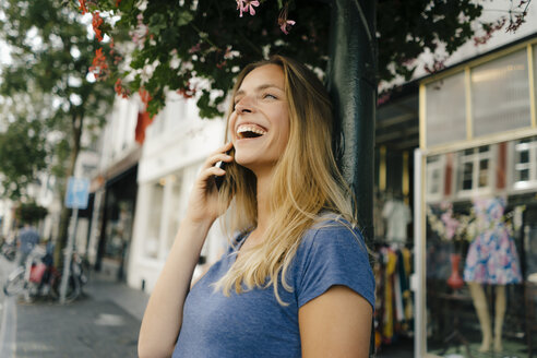Niederlande, Maastricht, lachende junge Frau beim Telefonieren in der Stadt - GUSF01513