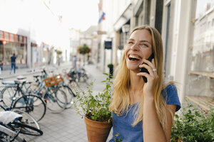 Niederlande, Maastricht, lachende junge Frau beim Telefonieren in der Stadt - GUSF01517
