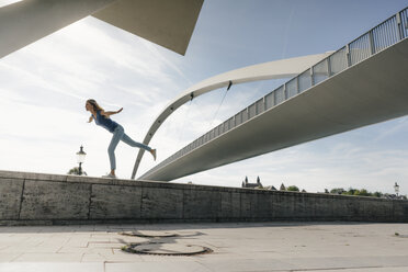 Niederlande, Maastricht, junge Frau balanciert auf einer Mauer an einer Brücke - GUSF01524