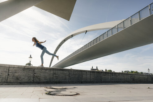 Netherlands, Maastricht, young woman balancing on a wall at a bridge - GUSF01524