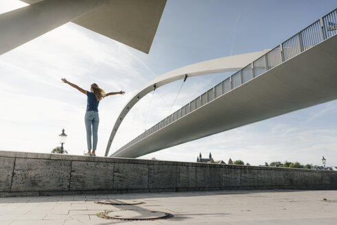 Niederlande, Maastricht, junge Frau steht auf einer Mauer an einer Brücke - GUSF01525