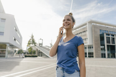 Niederlande, Maastricht, glückliche junge Frau am Handy in der Stadt - GUSF01531