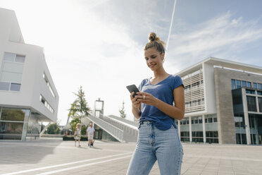 Netherlands, Maastricht, smiling young woman using cell phone in the city - GUSF01532