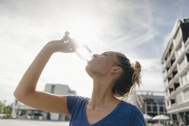 Netherlands, Maastricht, young woman drinking from bottle in the city - GUSF01533