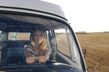 Happy young woman driving camper van in rural landscape - GUSF01545