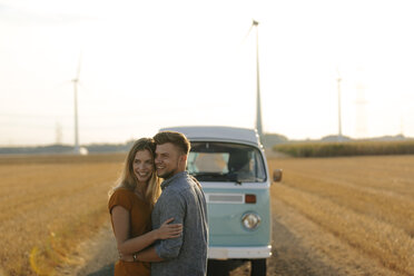 Happy affectionate young couple at camper van in rural landscape - GUSF01559