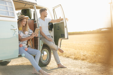 Young couple relaxing at camper van in rural landscape - GUSF01574