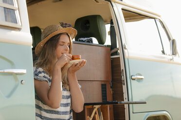 Young woman enjoying a cup of coffee in camper van - GUSF01575