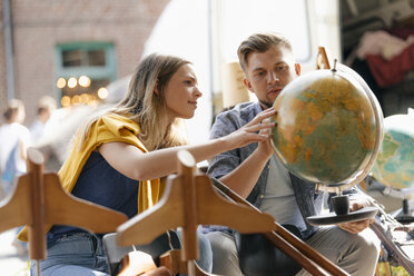 Belgium, Tongeren, young couple examining globe on an antique flea market - GUSF01584