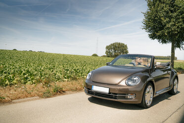 Couple kissing in convertible car on a country road - GUSF01618