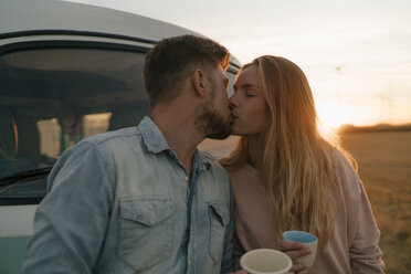 Young couple kissing at camper van in rural landscape - GUSF01628