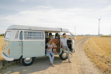 Young couple relaxing in camper van in rural landscape - GUSF01656