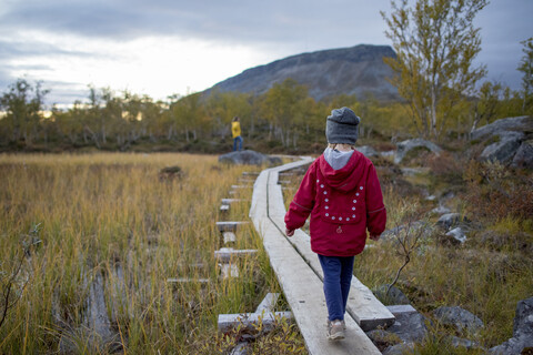 Finland, Lappland, Kilpisjaervi, girl on boardwalk, rear view stock photo