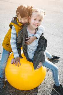 Porträt von zwei Kindern, die sich mit einem Gymnastikball vergnügen - HMEF00093