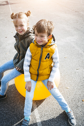 Porträt von zwei Kindern, die sich mit einem Gymnastikball vergnügen, lizenzfreies Stockfoto