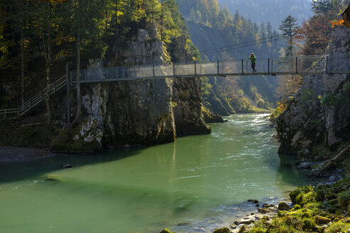 Österreich, Tirol, Wanderer auf Hängebrücke mit Blick auf die Tiroler Ache im Herbst - LBF02254