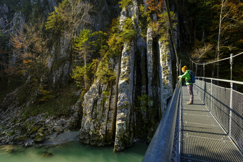 Österreich, Tirol, Wanderer auf Hängebrücke mit Blick auf die Tiroler Ache im Herbst - LBF02255