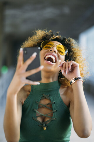 Porträt einer lachenden jungen Frau mit Smartphone im Freien, lizenzfreies Stockfoto